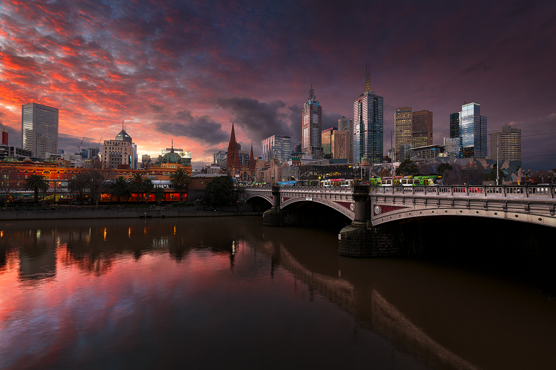 The buildings of Melbourne witness a fiery sunset over the Yarra River.